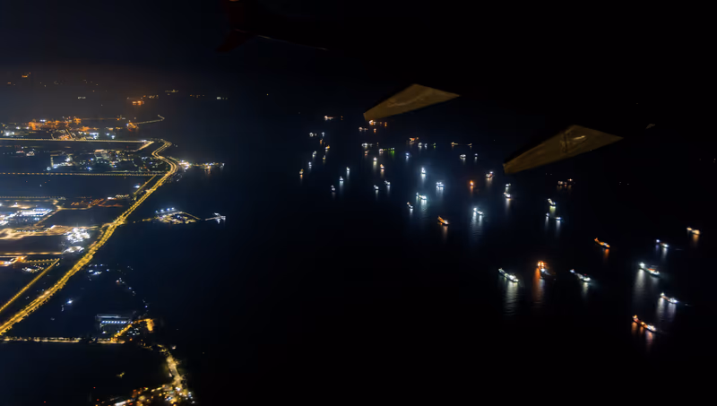 夜色机翼下，海面船灯闪烁，左岸城市灯火