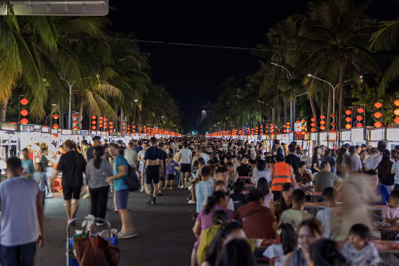 红灯笼映照的夜市人群与棕榈树