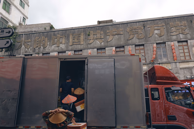 红卡车前，斗笠工人搬运货物