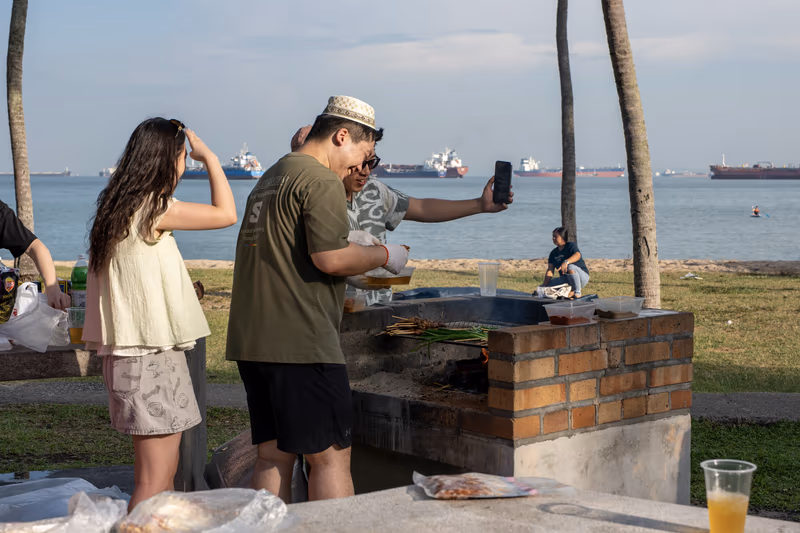 阳光沐浴下的海边烧烤聚会，一名男子正在拍照留念