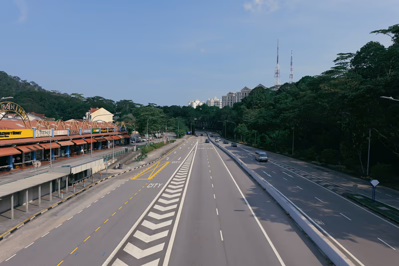 蓝天白云下宽阔的街道，路旁红顶小店与绿树相映成趣