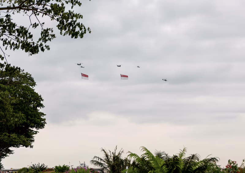 悬挂新加坡国旗的直升机在空中飞行