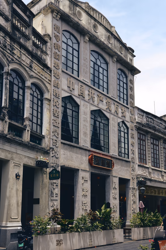 灰色老建筑立面刻满醒目标语，拱窗对称排列