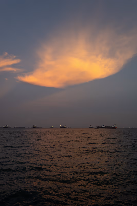 夕阳燃起的橙黄色云层与宁静海面上的船只